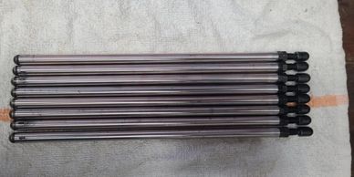 Eight metal rods with black caps neatly aligned on a towel.