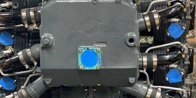 A newly painted radial engine on a workshop table, with blue tape on parts.