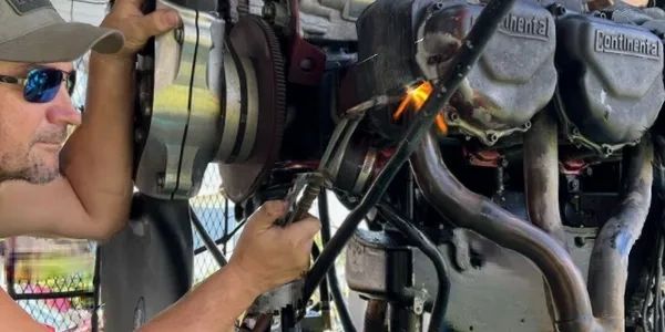 Man welding on a Continental aircraft engine outdoors.