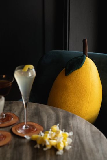 A cocktail on a table with a Lemon cushion in the background