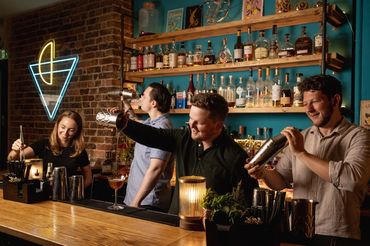 A group photo of bartenders working behind a cocktail bar 