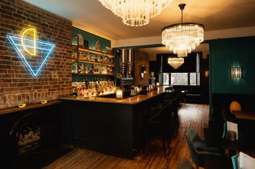 A wide shot of a cocktail bar with chandeliers 