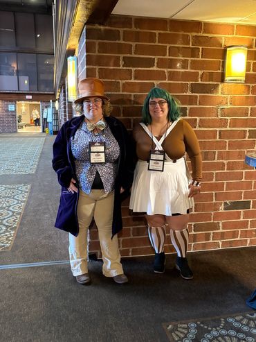 Two people in creative costumes standing indoors.