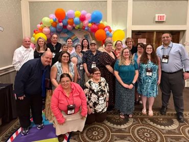Group photo with colorful balloon arch background.