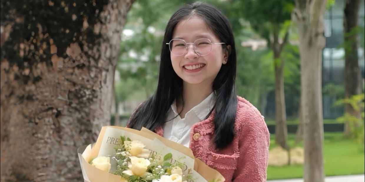 Young woman smiling with a bouquet of white flowers.