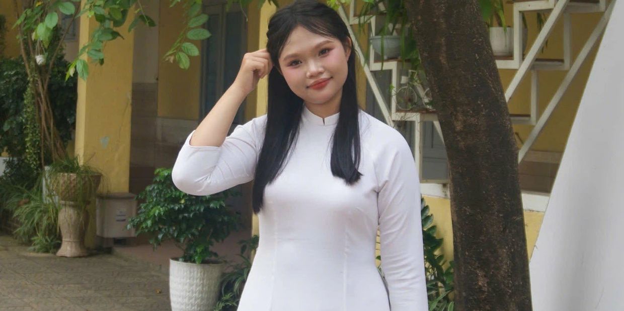 Young woman in traditional white dress smiling outdoors.