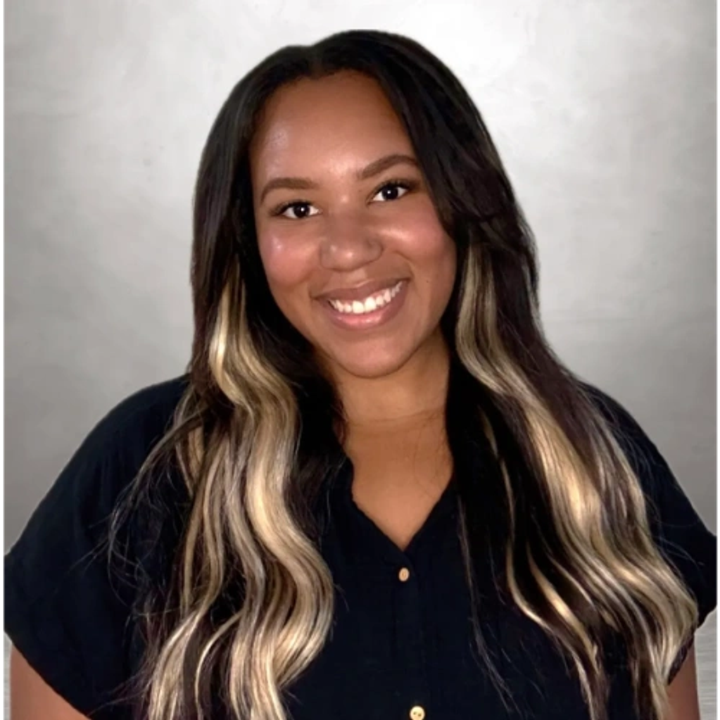 Smiling woman with long dark hair and blonde highlights.