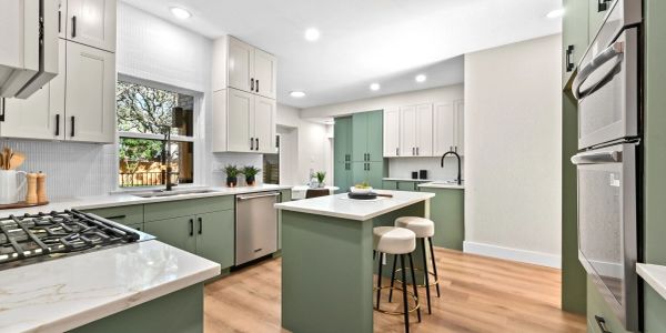 Modern kitchen with green cabinets and white countertops.