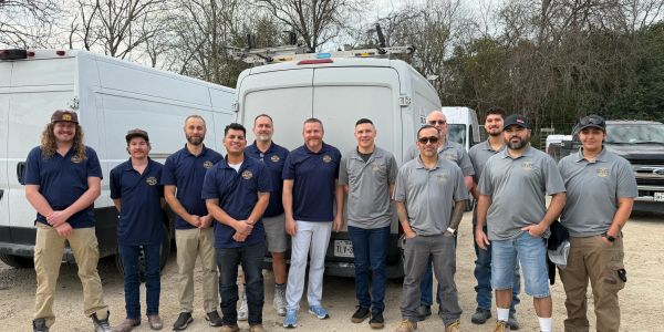 Group of men standing in front of vans outdoors.