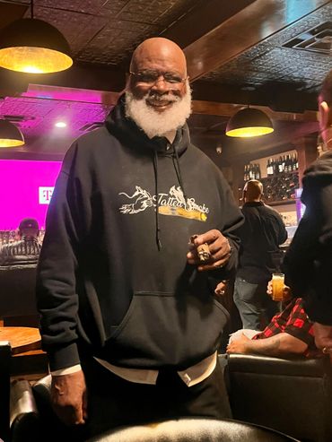 Smiling man with white beard in a hoodie at a cozy bar.