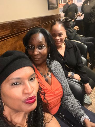 Three women posing together indoors, smiling and relaxed.