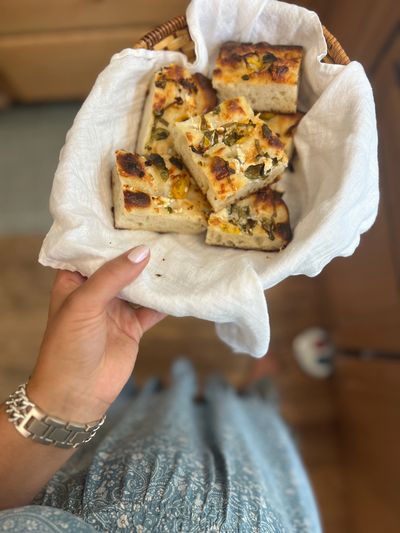 pieces of baked sourdough focaccia in a towel-lined bread basket
