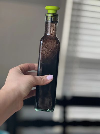 woman's hand holding a glass bottle with mocha syrup in it