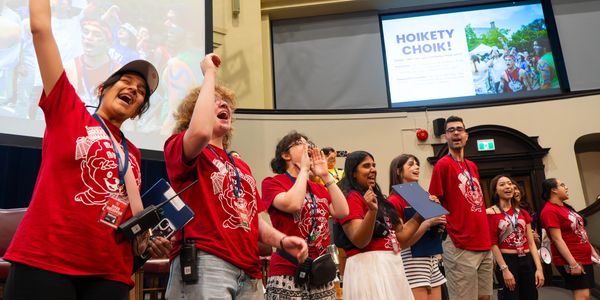 Group of people in red shirts cheering indoors.