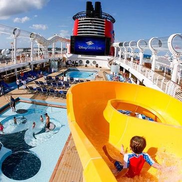 The deck of a Disney Cruise ship with lounge chairs, bright blue sky, and ocean views.