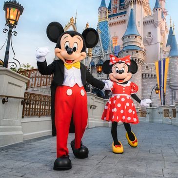 Mickey and Minnie Mouse happily posing together at Disney World with castle in background.
