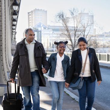 Three friends walk side by side on a city sidewalk during a chilly winter day.