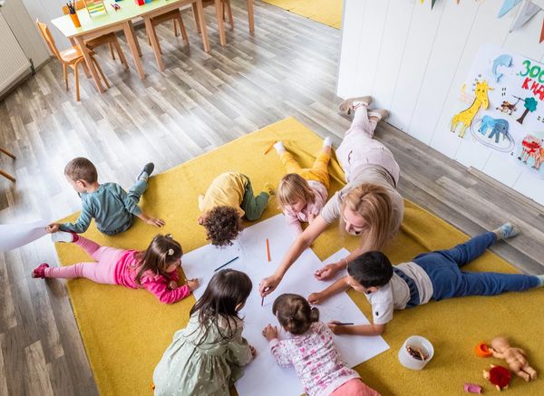 Little cute children are in kindergarten and they all have a piece of paper