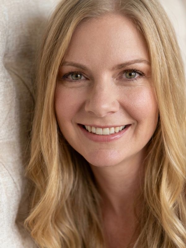 Close-up of a smiling woman with blonde hair.
