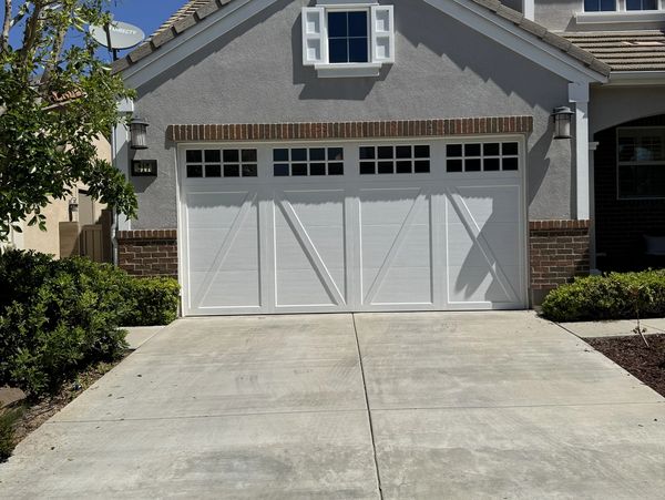White garage door with windows on a suburban house driveway.
