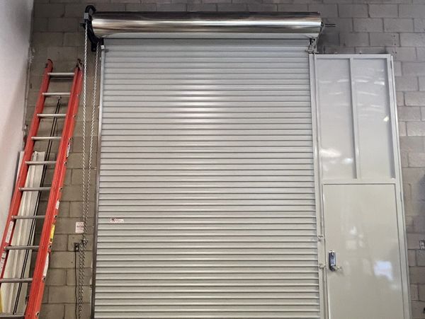 Closed industrial metal rolling door with a ladder beside it.