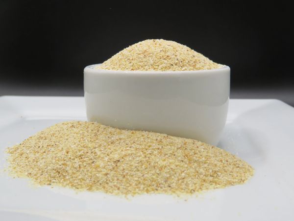 A white bowl filled with fine yellow cornmeal on a white plate.