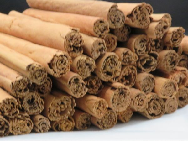 A pile of cinnamon sticks stacked on a white plate.