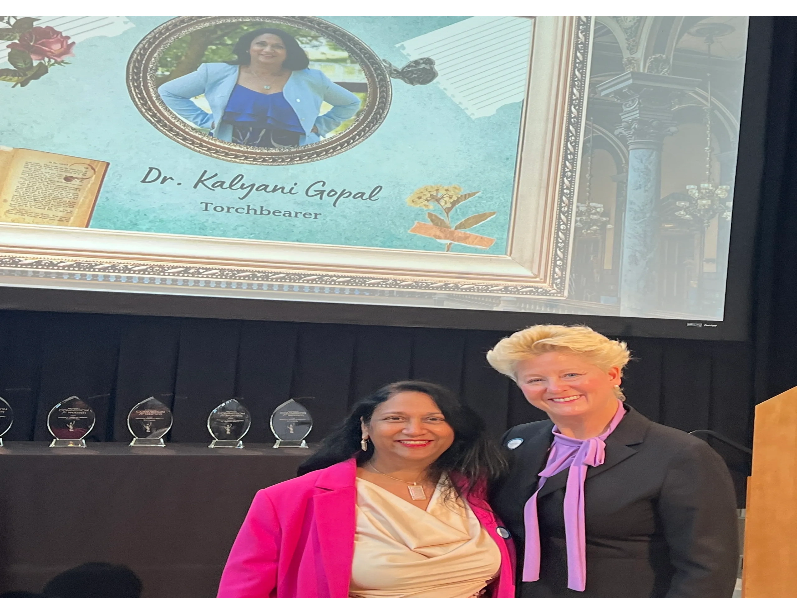 Dr. Kalyani Gopal honored as Torchbearer with a smiling companion at an award event.