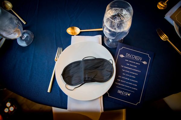 Image showing place setting at Discovery including blind fold, program, and dishes.