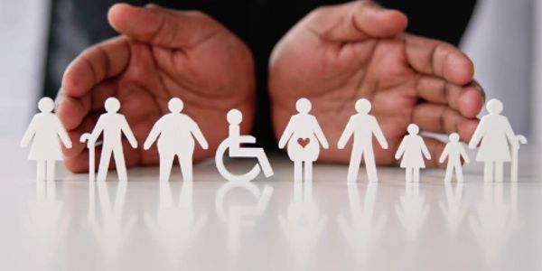 Mãos protegendo figuras de papel de uma família diversificada.