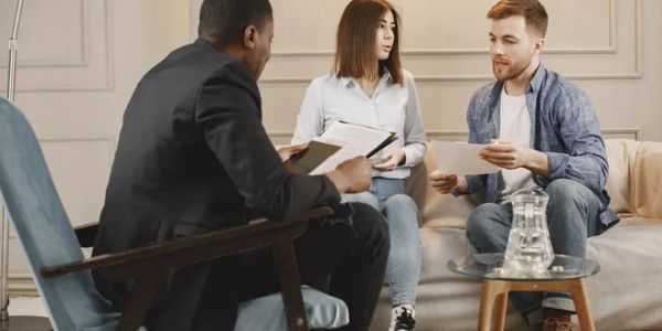 Three people having a discussion in a living room setting.