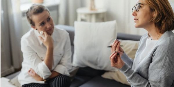Two women engaged in a serious conversation on a couch.