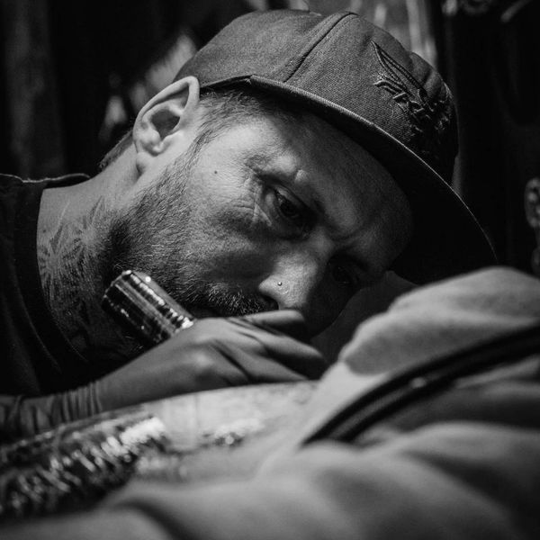Man focused while tattooing in black and white.