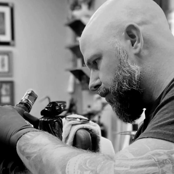 A tattoo artist focused on his work.