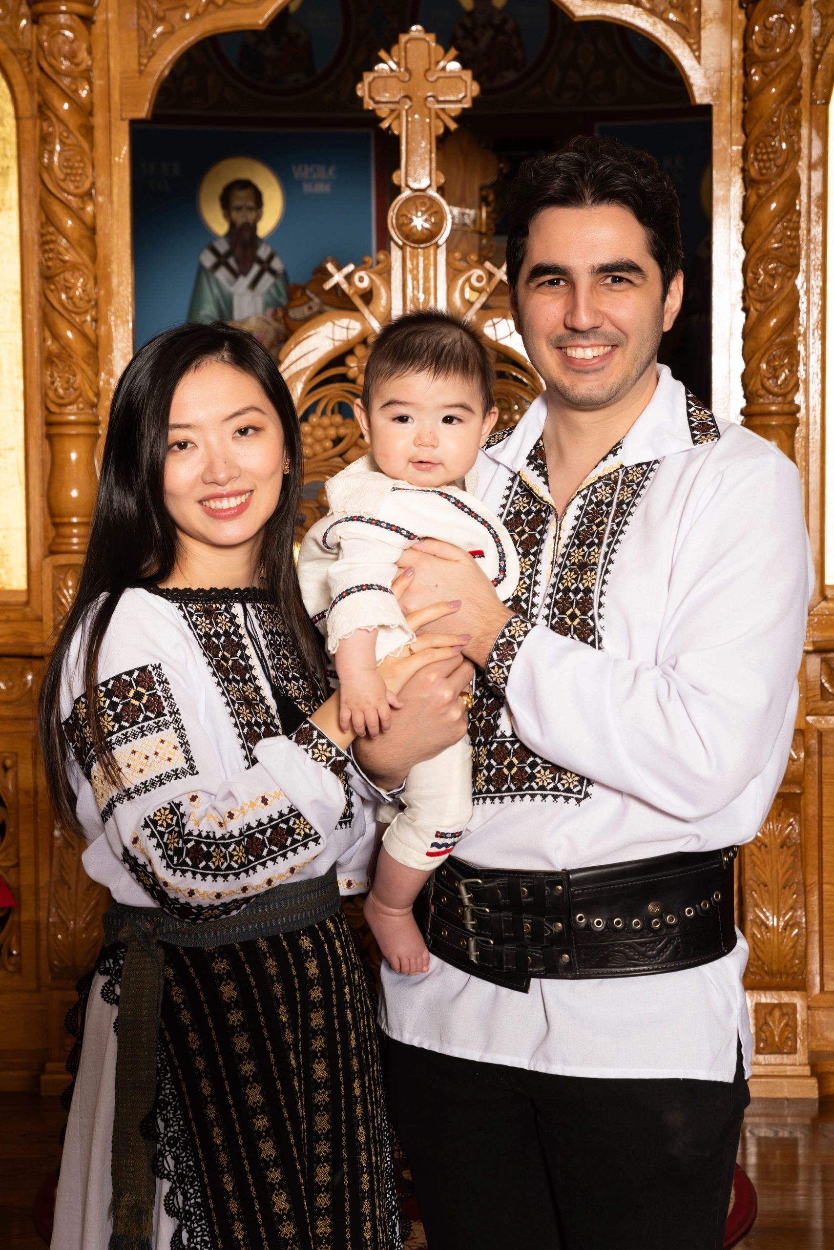 A family dressed in traditional embroidered clothing poses in a wooden church interior.