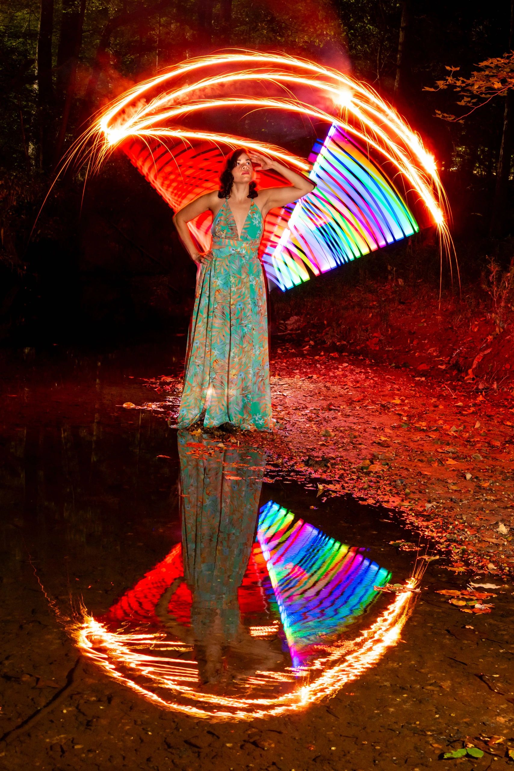 Woman in floral dress with colorful light painting and reflection.