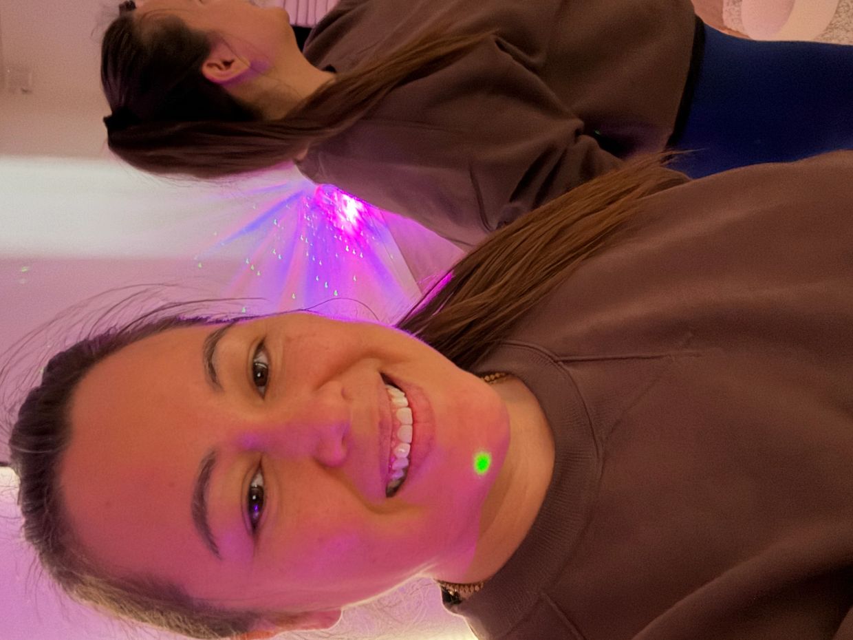 Adele Choh Zin reiki sound healing facilitator smiling in a portal shaped mirror, soundbath seating