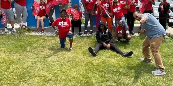 Group of people posing outdoors, many wearing red shirts.