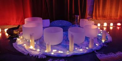 A serene arrangement of crystal singing bowls surrounded by candles and soft lights.