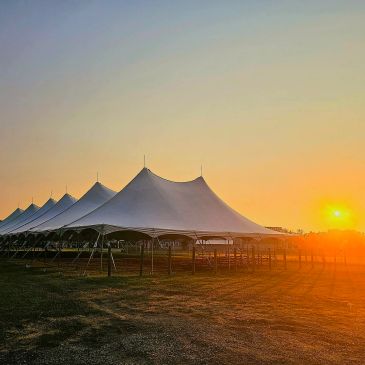 Large white event tents lined up under a sunset sky.