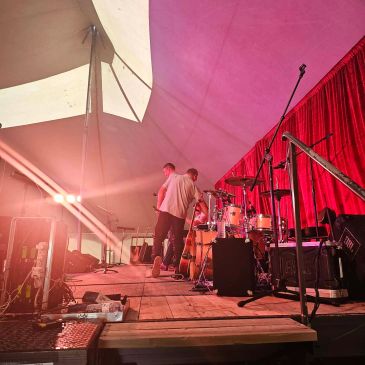 Musicians preparing on stage with red curtains and warm lighting.