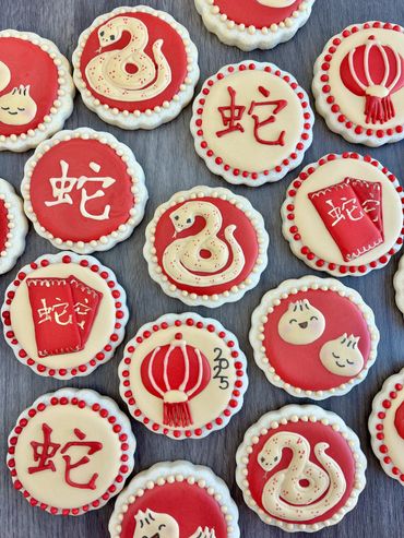 Red and white cookies decorated with snakes, lanterns, and Chinese characters.