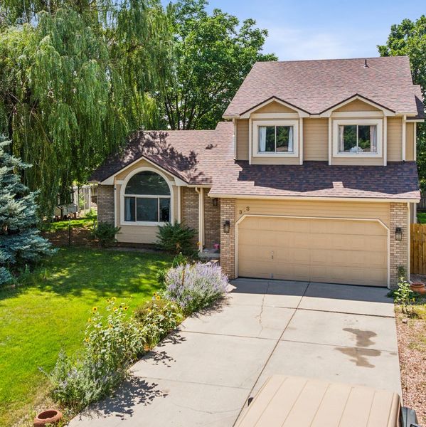 Exterior of the house with a two car garage, large windows and greenery surrounding the home.
