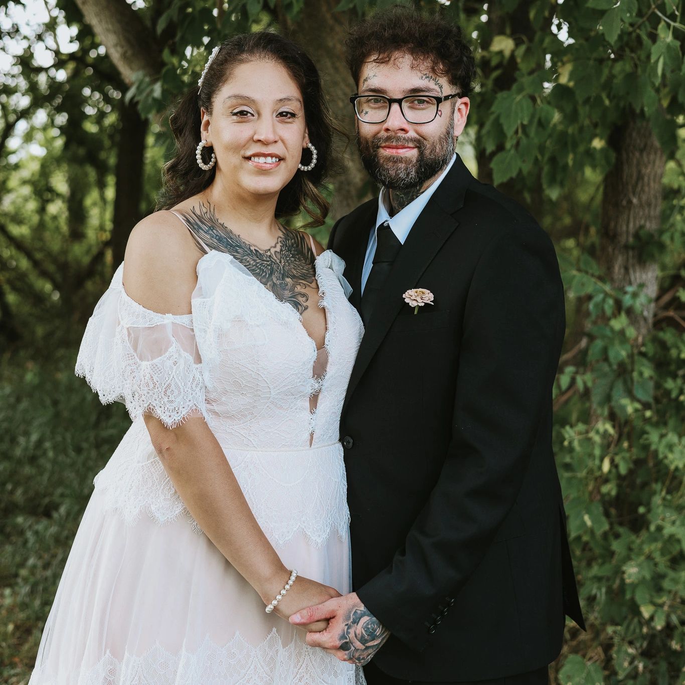 Bride and groom holding hands outdoors, smiling.