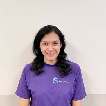 Smiling woman wearing a purple Cyan Swim Academy T-shirt against a plain background.