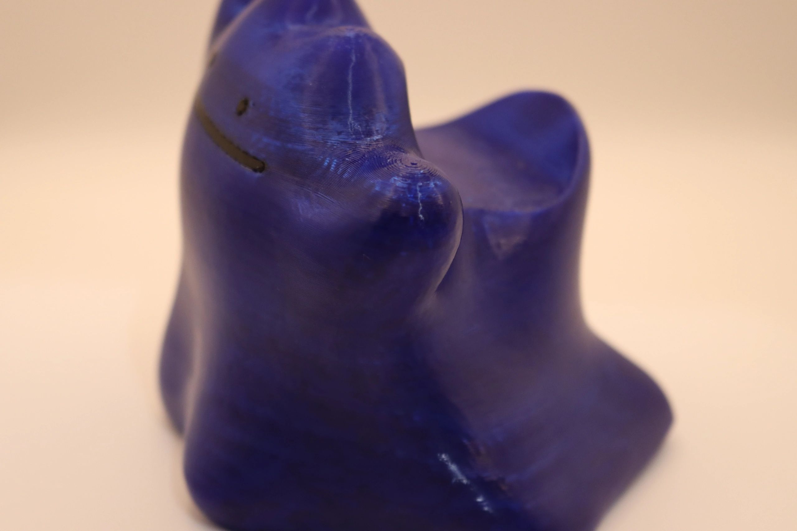 Close-up of a blue 3D-printed abstract cat figurine with a smiling face.