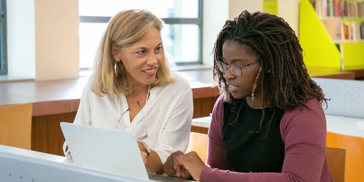  two women talking to each other and also visible on a laptop screen.