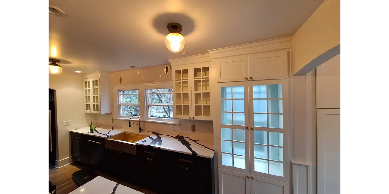 Modern kitchen with black and white cabinetry and marble countertops.