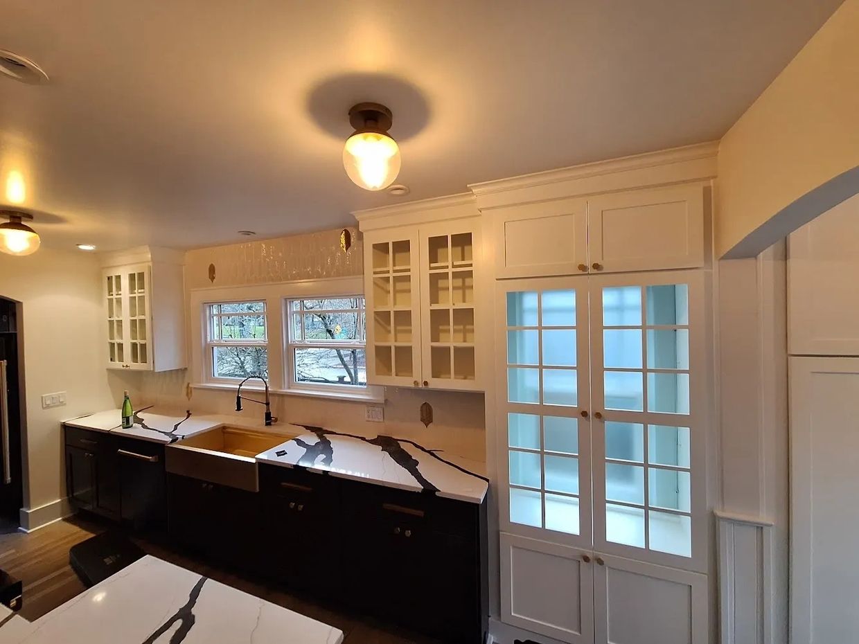 Modern kitchen with black and white cabinetry and marble countertops.