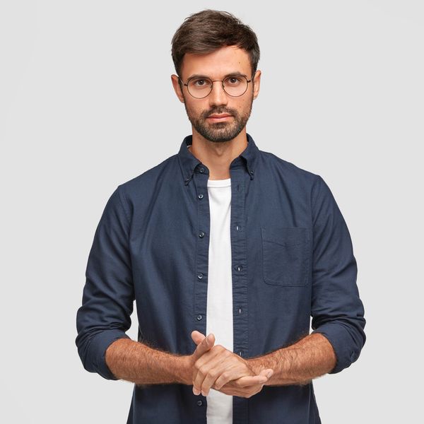 Man with glasses in a navy shirt looking serious.